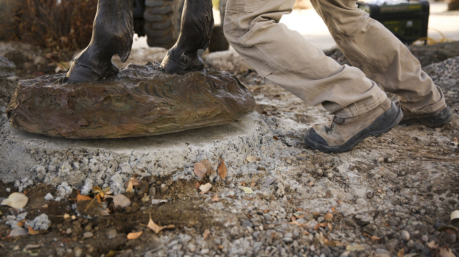Dan Rogers leans into the statue to help line it up properly on the concrete slabs